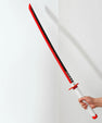 Hand holding red and black anime katana sword with white handle against plain wall
